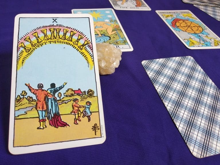 The Ten of Cups tarot card showing a family under a rainbow of cups, symbolizing emotional fulfillment and harmony