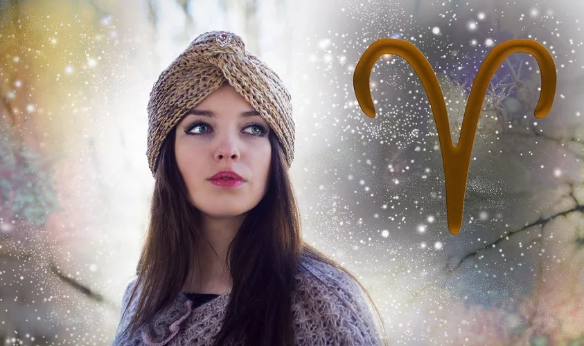 Woman wearing a woven hat, with a glittery bakcground with the Aries symbol