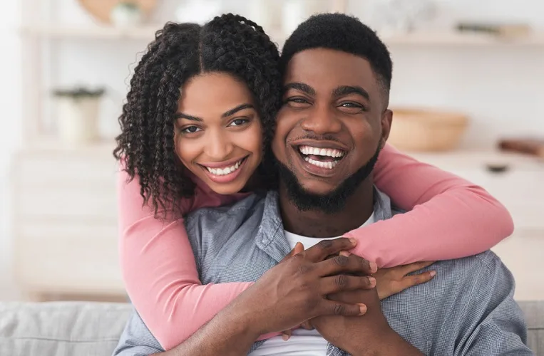 Loving young black couple hugging and smiling at the camera