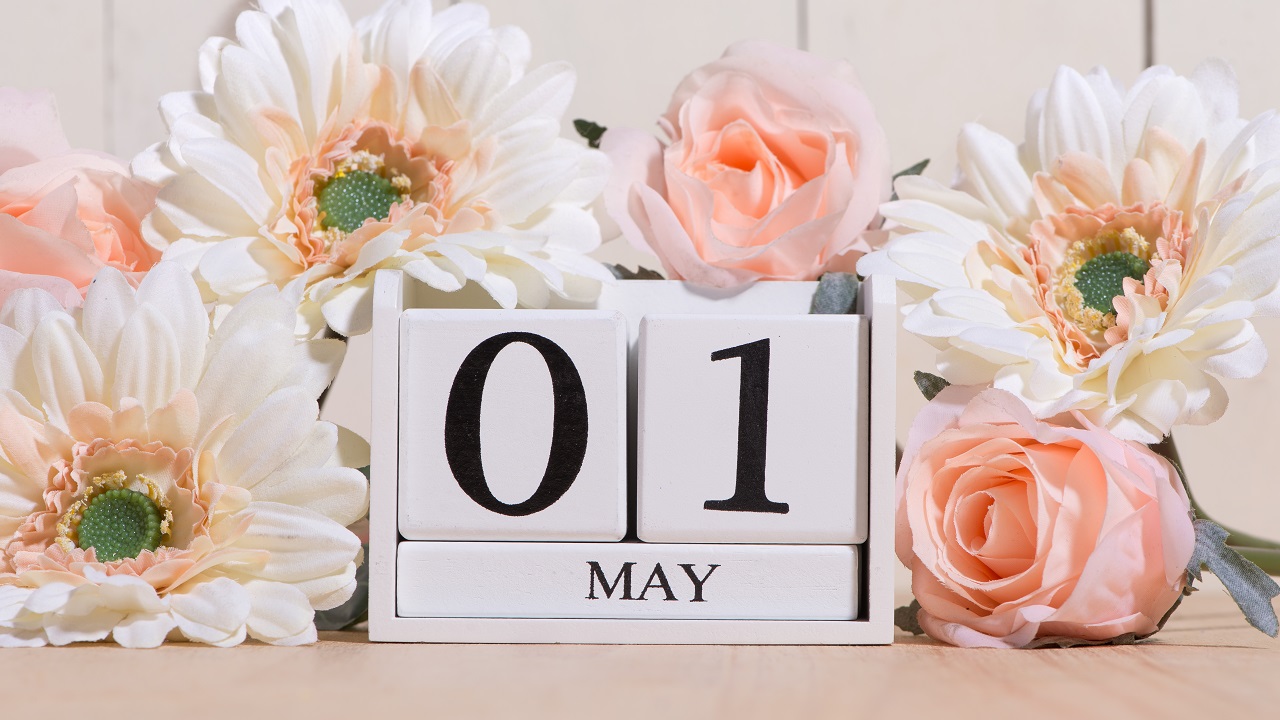 May 1st date on a simple clock calendar with pink flowers surrounding it