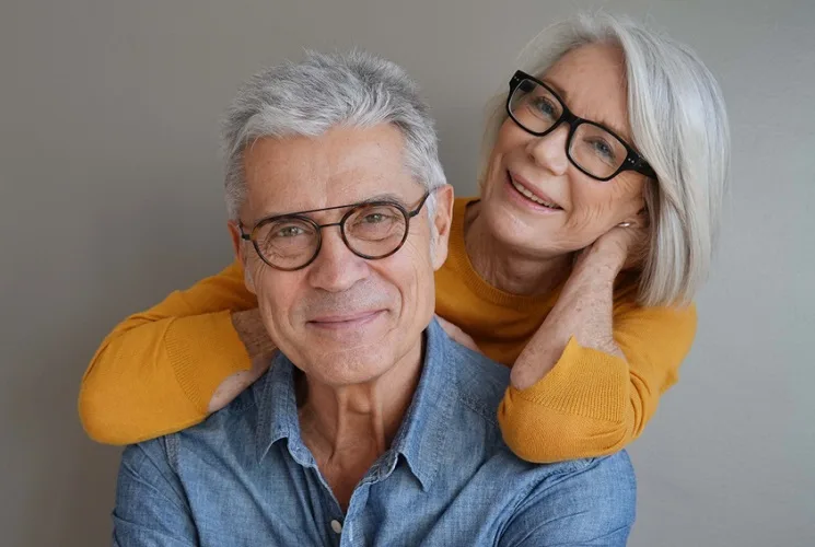 Senior couple wearing glasses with a grey background