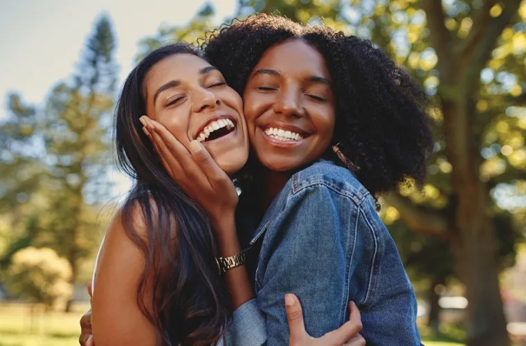 Two mixed raced women laughing and embracing each other