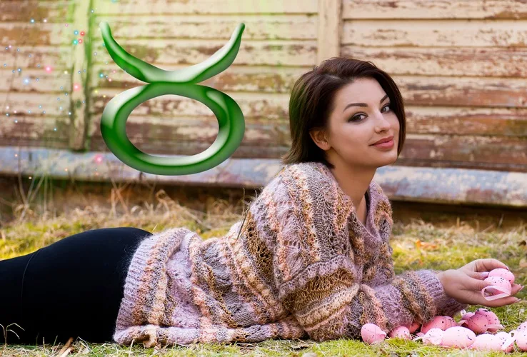 Woman laying down on grass with the Taurus symbol above her