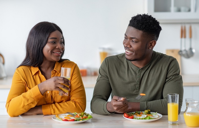 Young black couple talking and smiling while eating lunch and drinking