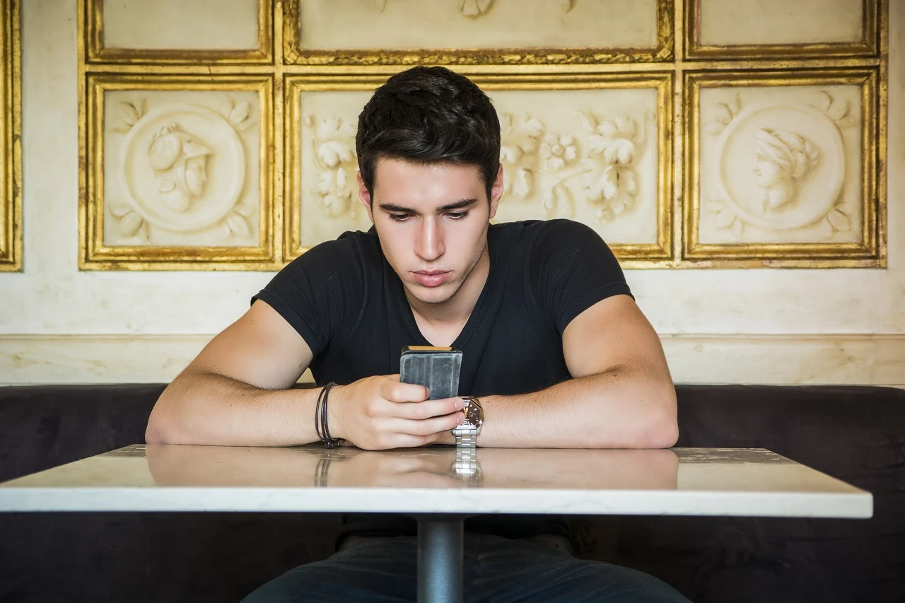 Man sitting in elegant cafeteria using cell phone